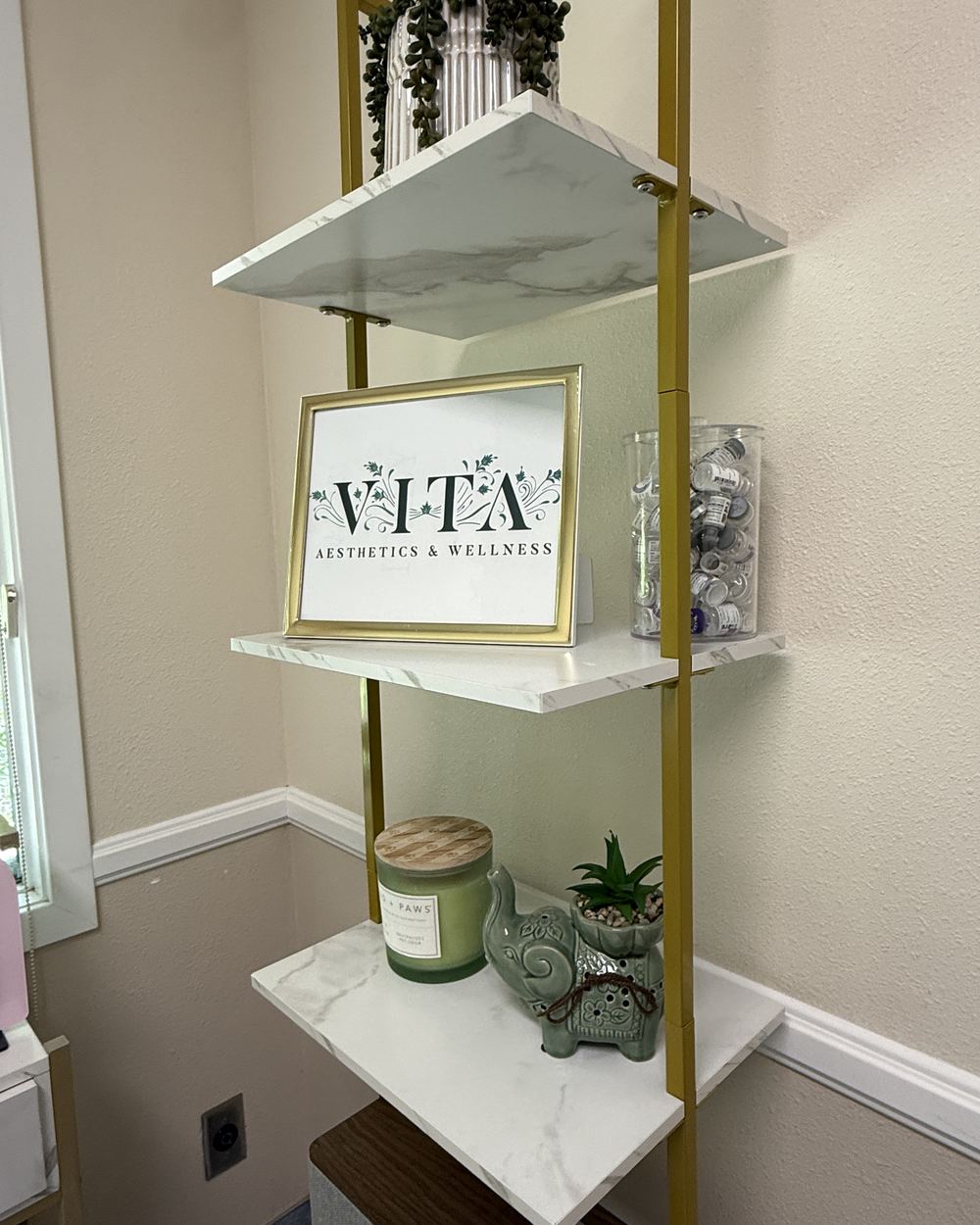 The Vita Aesthetics & Wellness sign on a marble shelf inside the Whittier treatment room